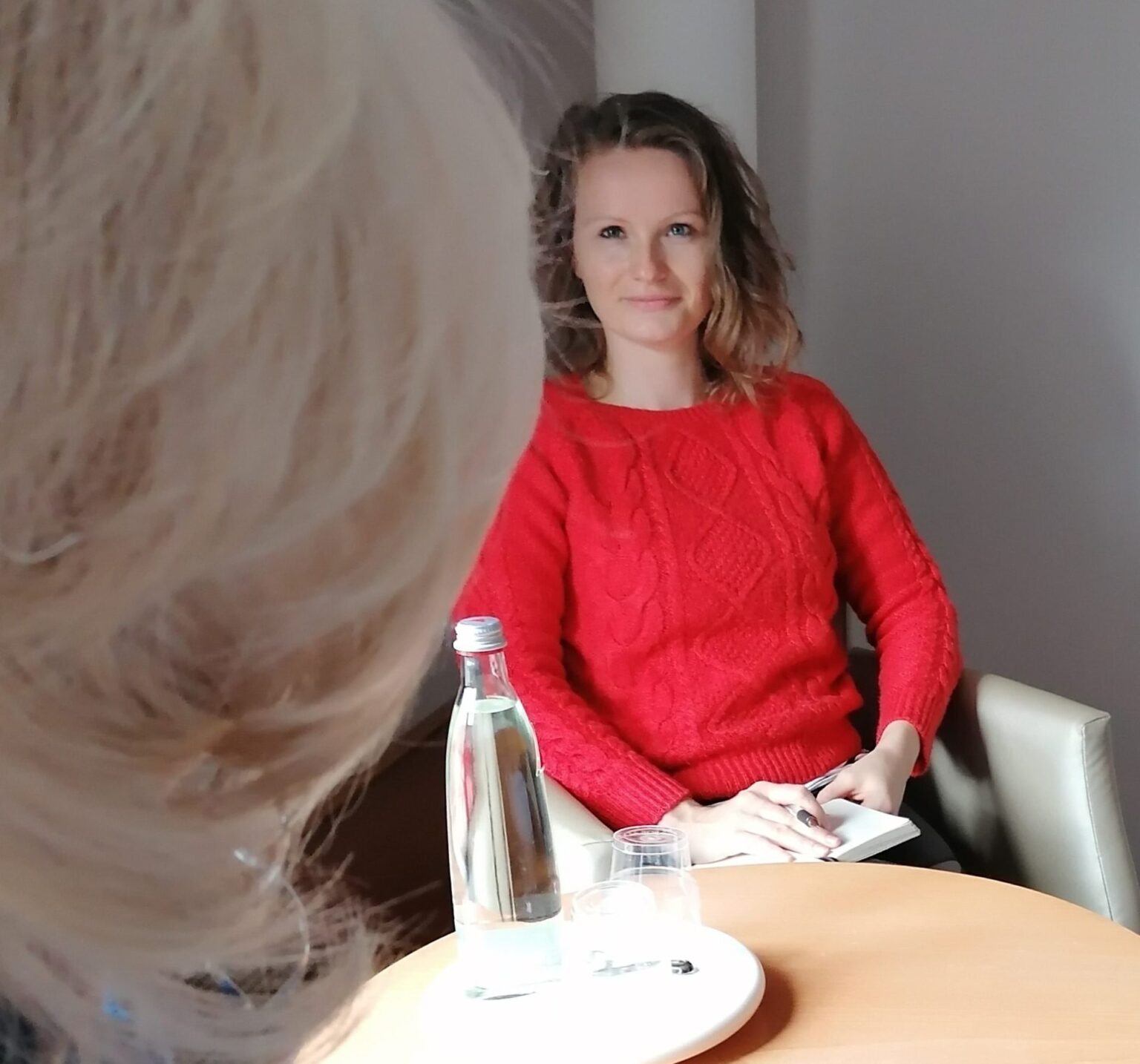 Camilla Jacob sitzt mit einer anderen Person am Tisch und hört zu